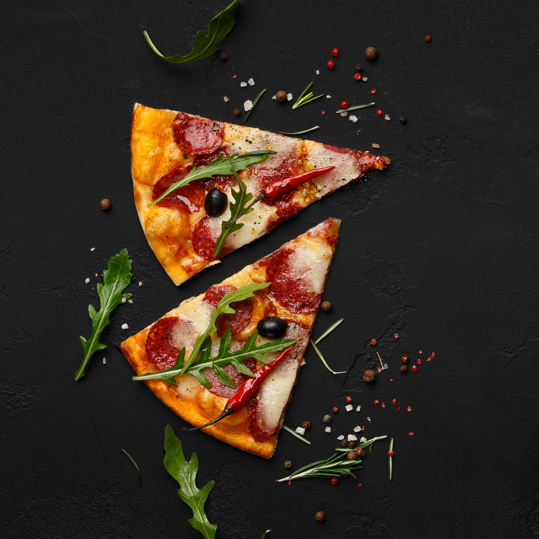 Pizza slices with rocket salad on black background